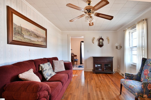 living room with light hardwood / wood-style flooring, ornamental molding, and ceiling fan