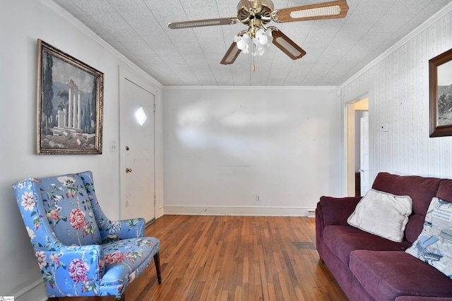 sitting room with dark wood-type flooring, ornamental molding, and ceiling fan