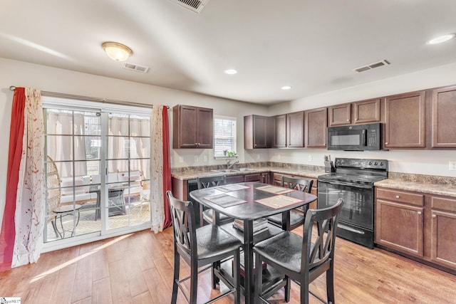 kitchen with dark brown cabinets, sink, light hardwood / wood-style floors, and black appliances