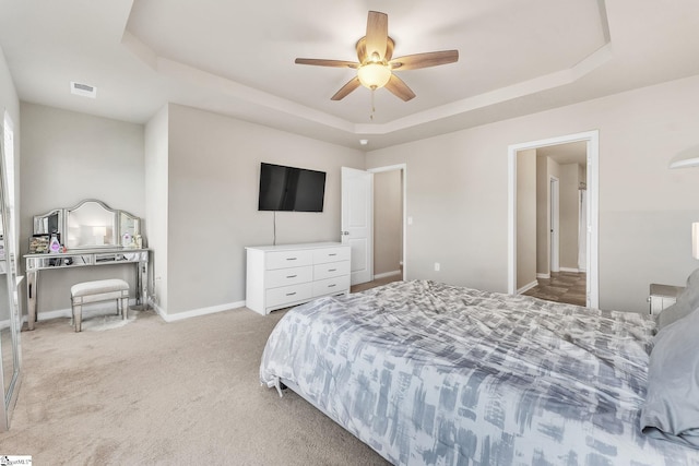 carpeted bedroom with a tray ceiling and ceiling fan