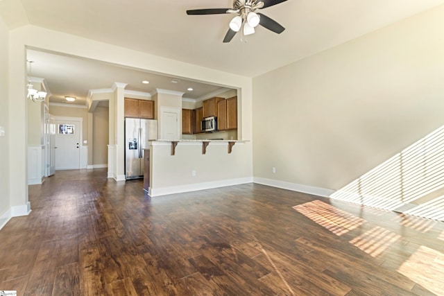 unfurnished living room featuring dark hardwood / wood-style flooring, ceiling fan with notable chandelier, and ornamental molding