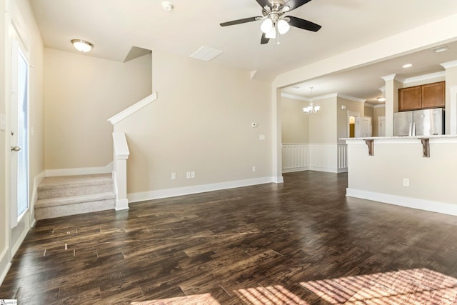 unfurnished living room with ceiling fan with notable chandelier, ornamental molding, and dark hardwood / wood-style floors