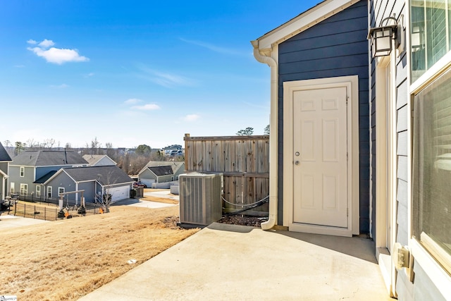 view of exterior entry with a patio and central air condition unit