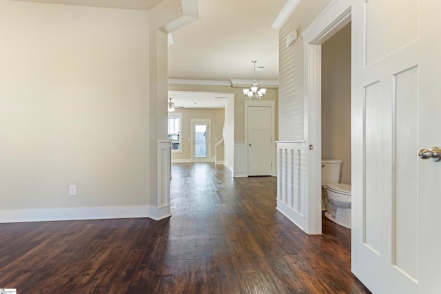 corridor with ornamental molding, an inviting chandelier, and dark hardwood / wood-style flooring