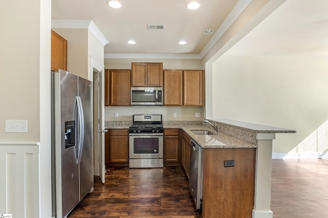 kitchen with sink, a breakfast bar, stainless steel appliances, light stone counters, and kitchen peninsula