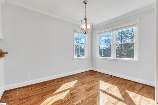 unfurnished dining area featuring crown molding, a notable chandelier, and light wood-type flooring