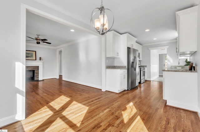 kitchen with decorative light fixtures, stainless steel appliances, white cabinets, and stone countertops