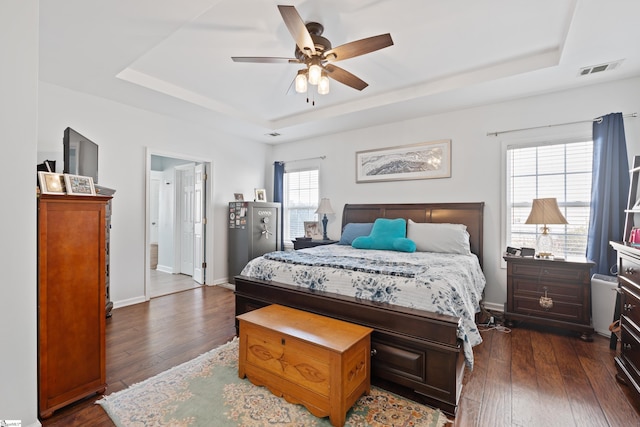 bedroom featuring dark wood-type flooring, ceiling fan, and a tray ceiling