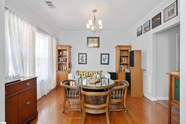 dining area with beverage cooler, a chandelier, breakfast area, crown molding, and light wood-type flooring