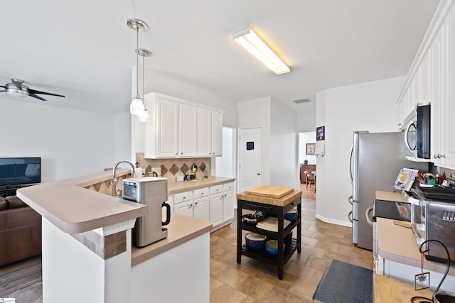 kitchen featuring ceiling fan, hanging light fixtures, white cabinets, decorative backsplash, and kitchen peninsula