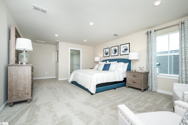 bedroom with light colored carpet and a spacious closet