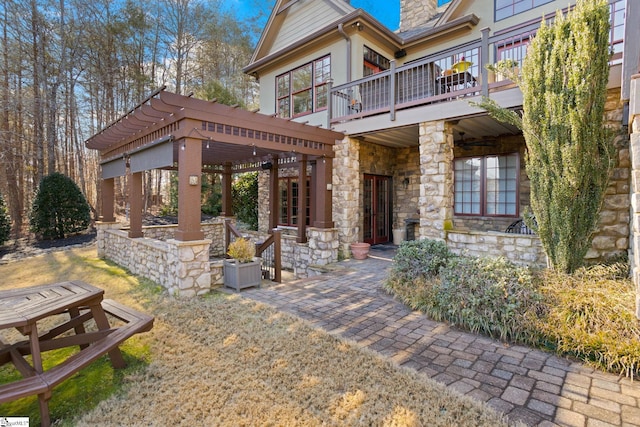 rear view of property featuring a balcony, a pergola, and a patio