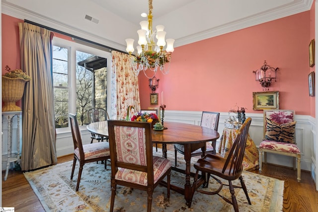 dining space featuring a notable chandelier, hardwood / wood-style flooring, and ornamental molding