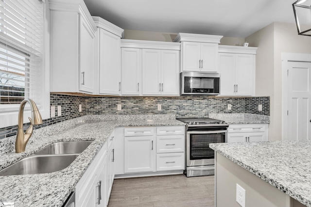 kitchen featuring tasteful backsplash, appliances with stainless steel finishes, sink, and white cabinets