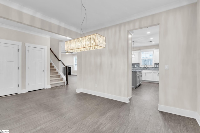 unfurnished dining area featuring hardwood / wood-style floors, crown molding, plenty of natural light, and sink