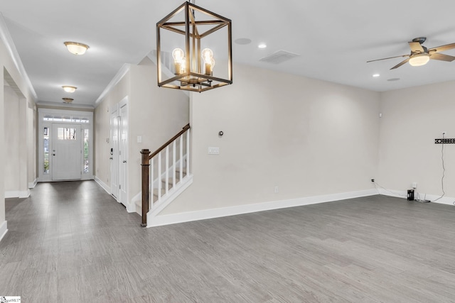 entrance foyer featuring ornamental molding, ceiling fan with notable chandelier, and dark hardwood / wood-style flooring