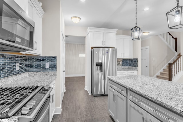 kitchen featuring white cabinetry, hanging light fixtures, stainless steel appliances, and light stone countertops