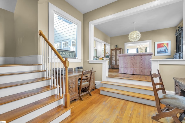 stairway featuring an inviting chandelier and hardwood / wood-style flooring