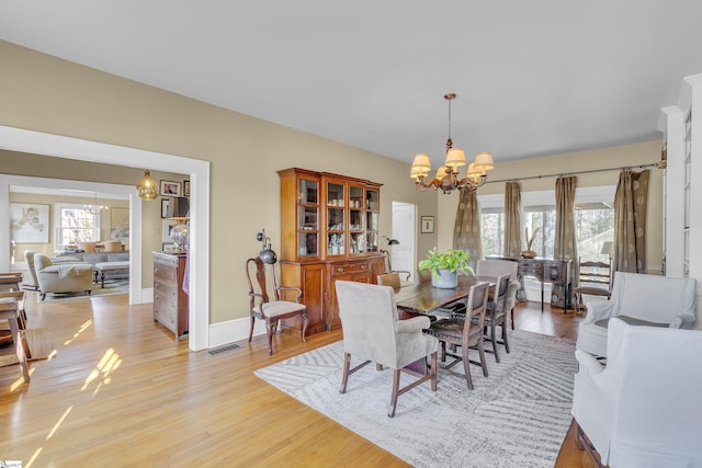 dining area with light hardwood / wood-style floors and a chandelier