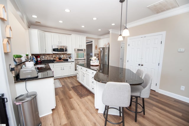 kitchen with sink, stainless steel appliances, white cabinets, a kitchen island, and decorative light fixtures