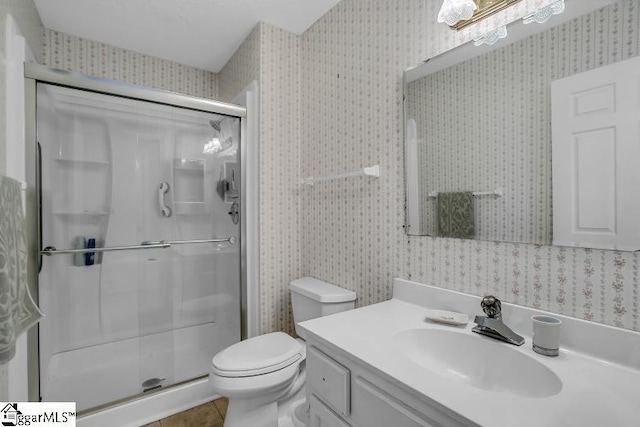 bathroom featuring tile patterned flooring, vanity, toilet, and a shower with shower door