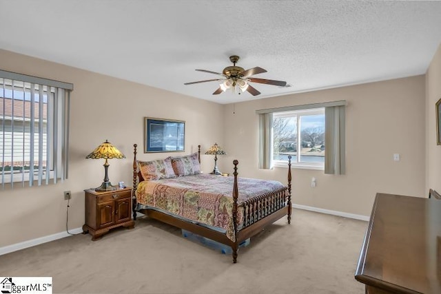 carpeted bedroom featuring ceiling fan and a textured ceiling