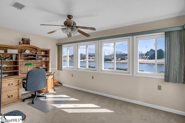 unfurnished office featuring light carpet, ceiling fan, and a water view