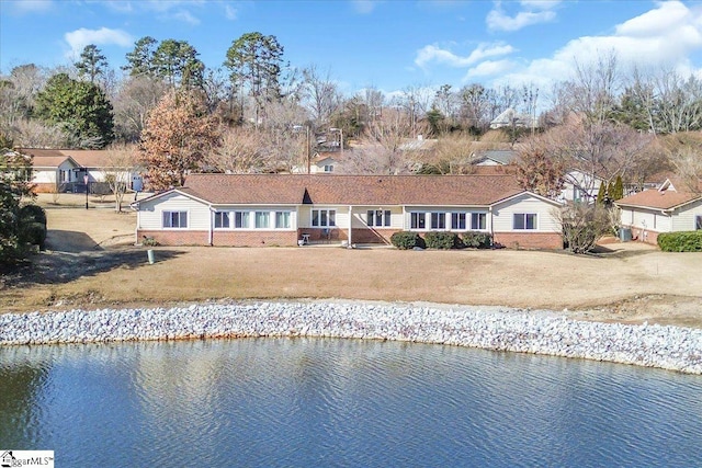 rear view of property featuring a lawn and a water view