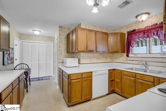 kitchen featuring white appliances, sink, and a textured ceiling