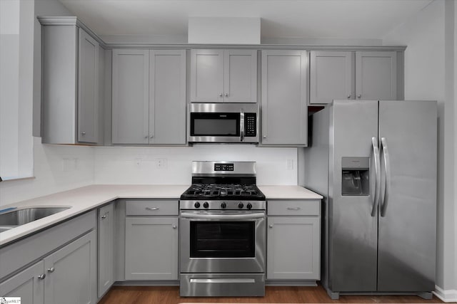 kitchen featuring appliances with stainless steel finishes, light hardwood / wood-style flooring, decorative backsplash, and gray cabinetry