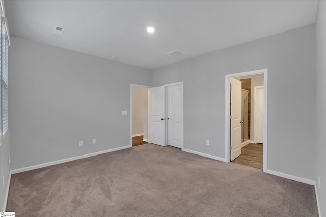 unfurnished bedroom with light colored carpet and ensuite bath