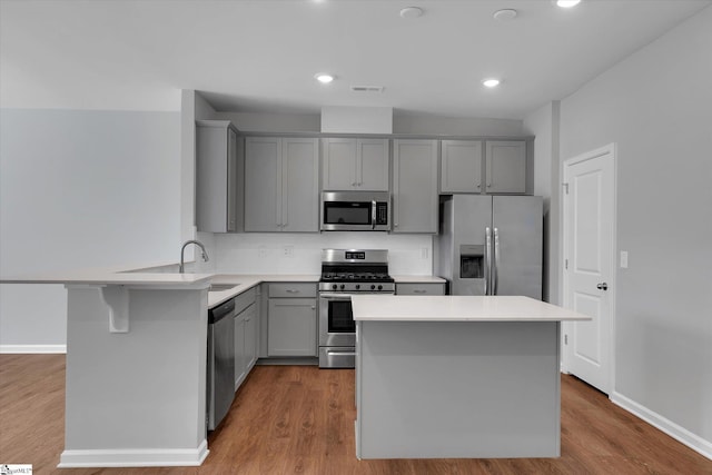 kitchen with gray cabinets, appliances with stainless steel finishes, tasteful backsplash, sink, and light wood-type flooring