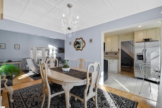 dining space featuring a notable chandelier, light hardwood / wood-style flooring, and french doors