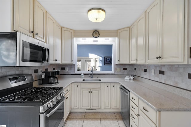 kitchen featuring sink, decorative backsplash, light tile patterned flooring, and appliances with stainless steel finishes