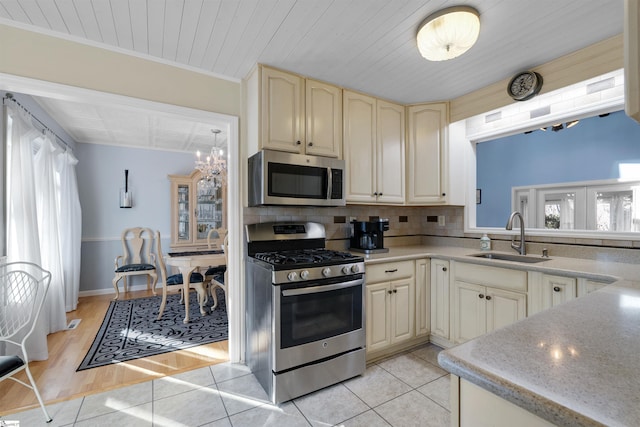 kitchen featuring appliances with stainless steel finishes, sink, backsplash, light tile patterned floors, and cream cabinetry