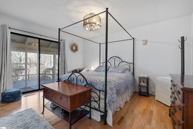 bedroom with a notable chandelier, access to exterior, a textured ceiling, and light wood-type flooring