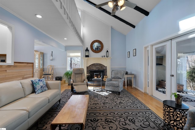 living room with ceiling fan, beam ceiling, high vaulted ceiling, ornamental molding, and light wood-type flooring