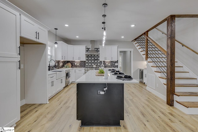 kitchen with white cabinetry, decorative light fixtures, a center island, decorative backsplash, and wall chimney range hood