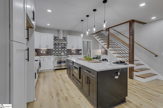 kitchen with white cabinets, high end stove, a center island, and wall chimney exhaust hood