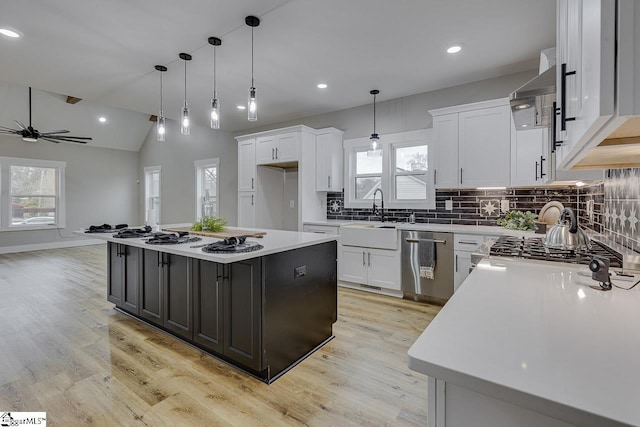 kitchen featuring dishwasher, a kitchen island, white cabinets, and decorative light fixtures