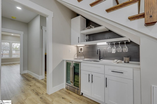 bar with white cabinetry, sink, wine cooler, decorative backsplash, and light hardwood / wood-style floors