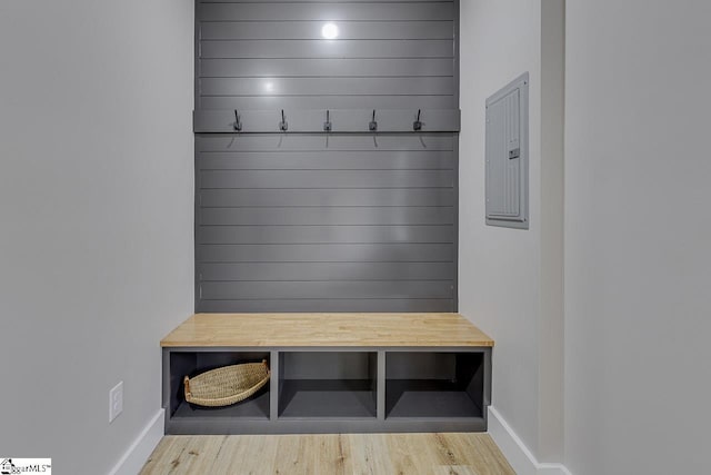 mudroom featuring electric panel, light wood-type flooring, and wood walls