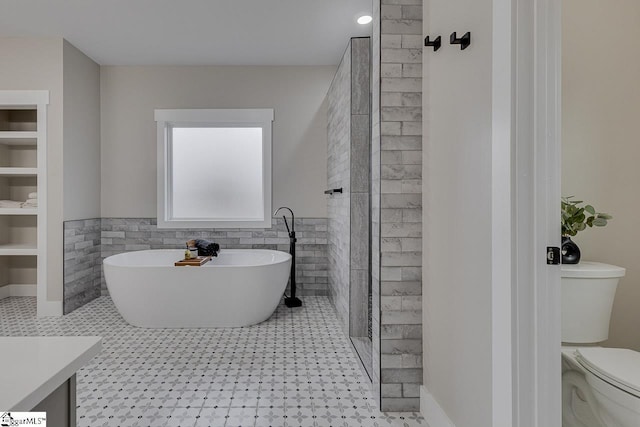 bathroom featuring built in shelves, toilet, tile walls, vanity, and a tub