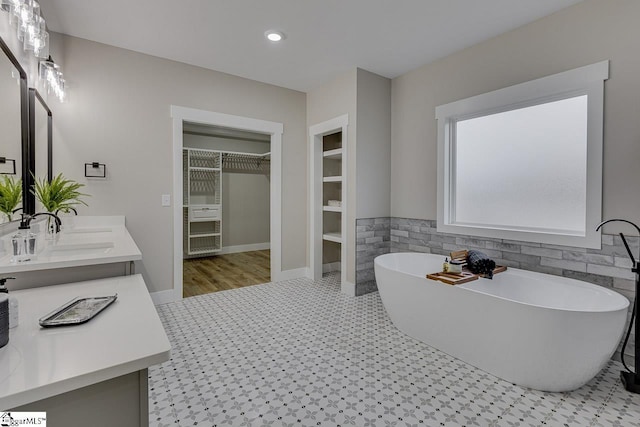 bathroom with vanity, a bath, and tile walls