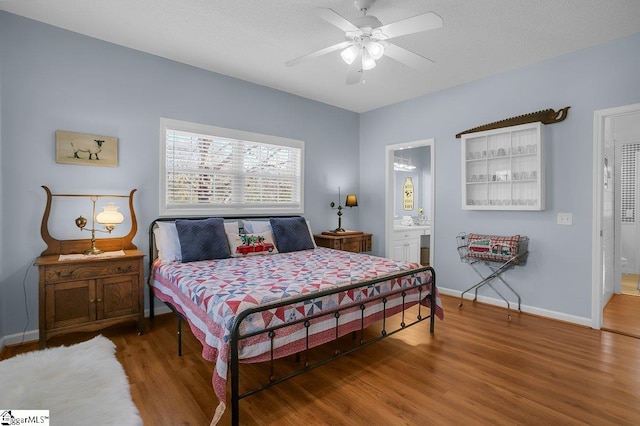 bedroom featuring wood-type flooring, ceiling fan, and ensuite bath