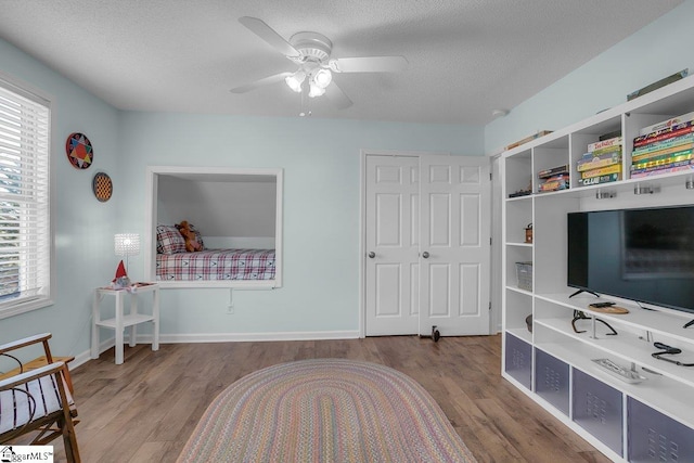 bedroom with ceiling fan, hardwood / wood-style flooring, and a textured ceiling