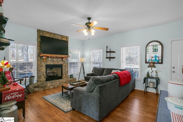 living room with ceiling fan, plenty of natural light, dark wood-type flooring, and a fireplace