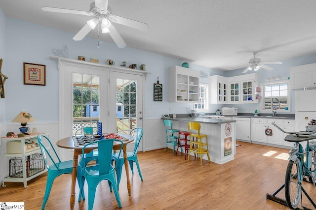 dining space with ceiling fan, sink, light hardwood / wood-style floors, and a textured ceiling