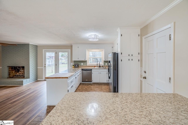 kitchen featuring ornamental molding, appliances with stainless steel finishes, a fireplace, and white cabinets