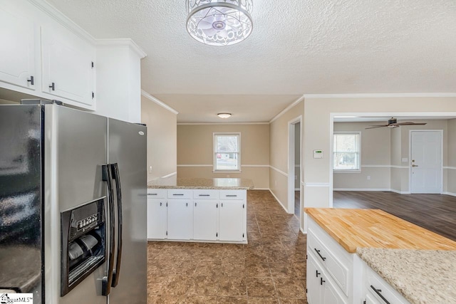 kitchen with white cabinetry, stainless steel fridge, ornamental molding, ceiling fan, and light stone countertops